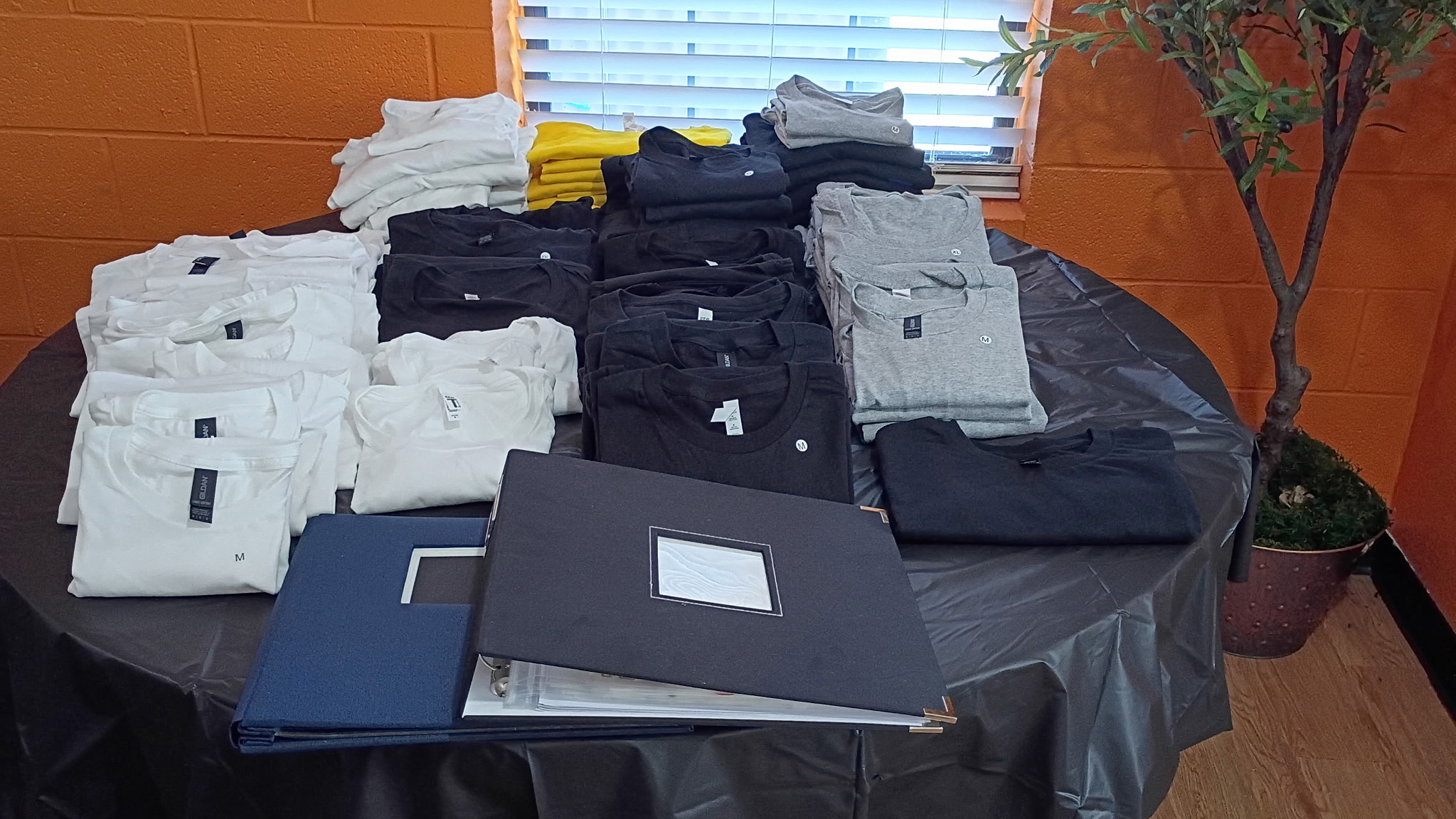 Black, white, gray, and yellow shirts arranged and ready for a Bee's Tees Experience event